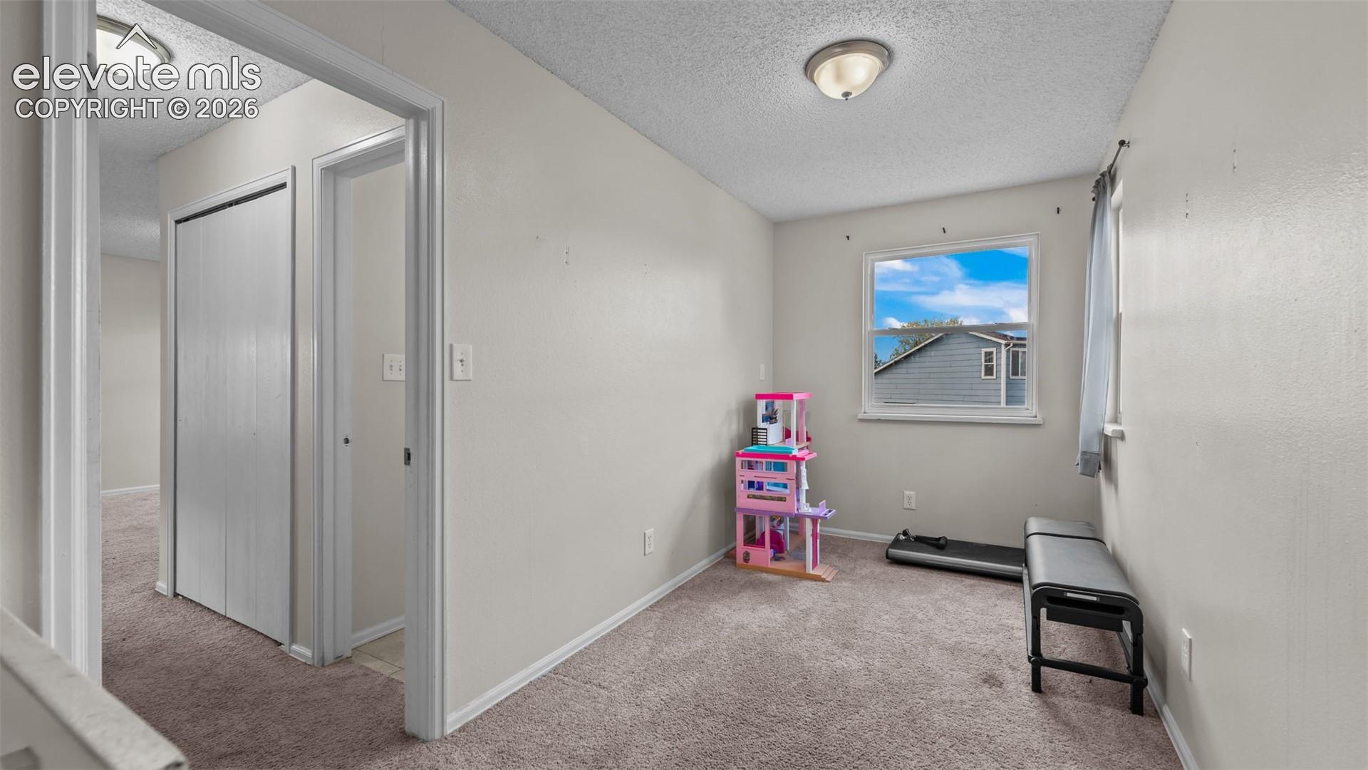 Interior space featuring neutral-toned carpeting, dual flush-mount ceiling light fixtures, a single-pane window, and a built-in closet with sliding doors