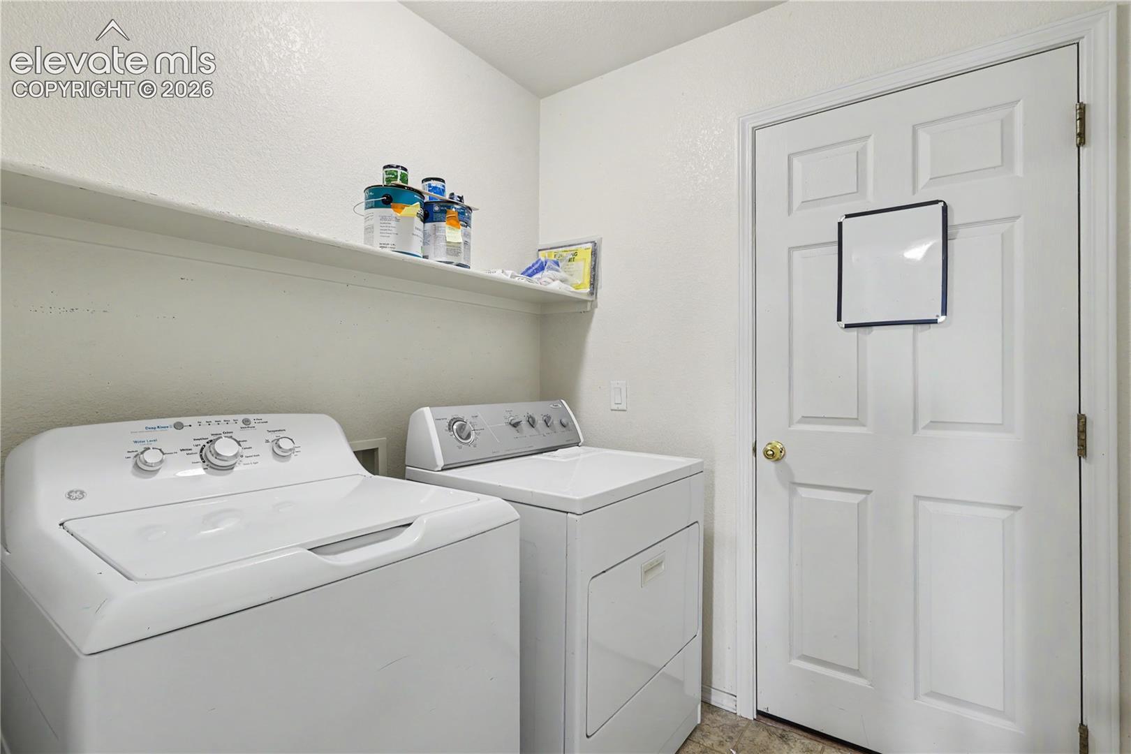 Dedicated laundry area featuring a built-in wall shelf and a paneled door with a brass doorknob
