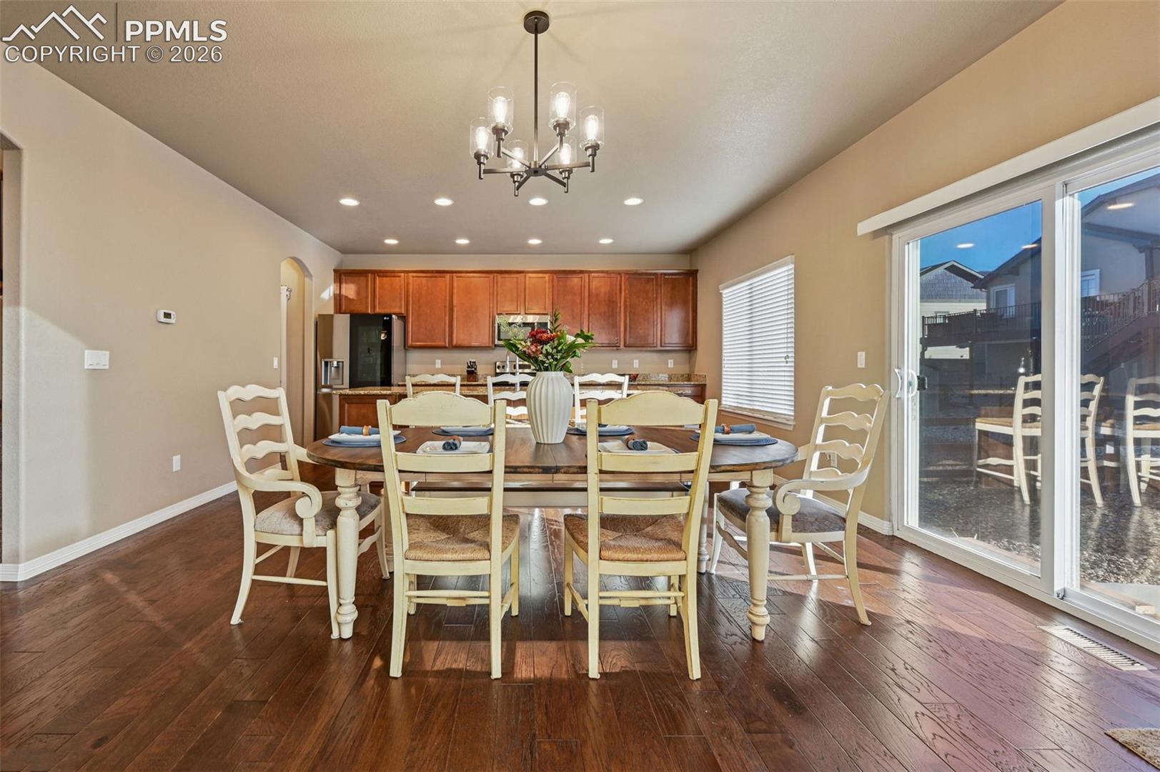 Dining room with arched walkways, dark wood-style floors, and a chandelier