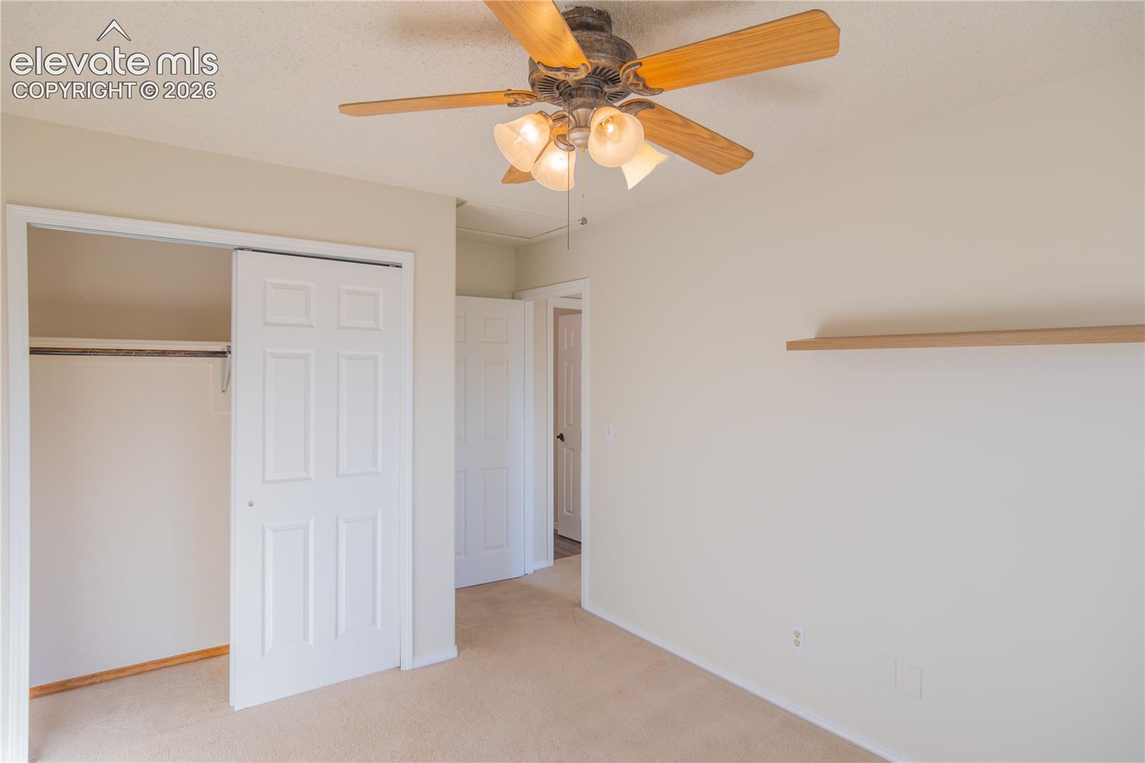 A spacious closet and decorative floating shelf provide practical storage and display options.