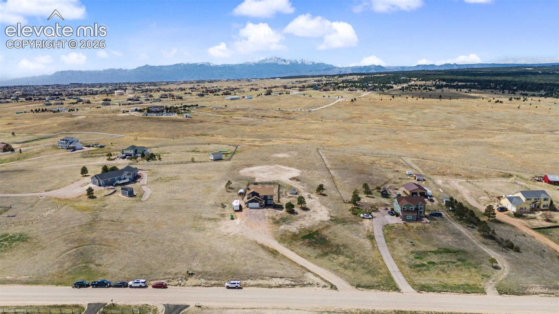 Aerial perspective of acreage featuring natural terrain, dirt-surface access roads, and mountain backdrops
