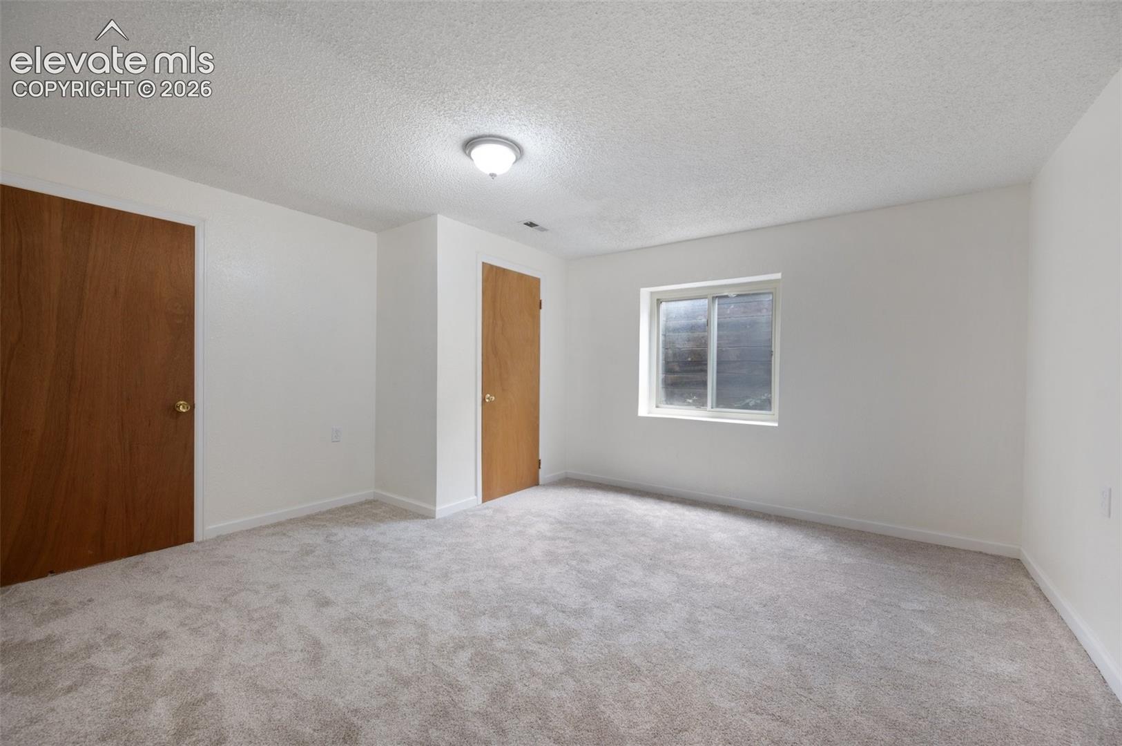 Unfurnished bedroom featuring carpet floors, a textured ceiling, and baseboards