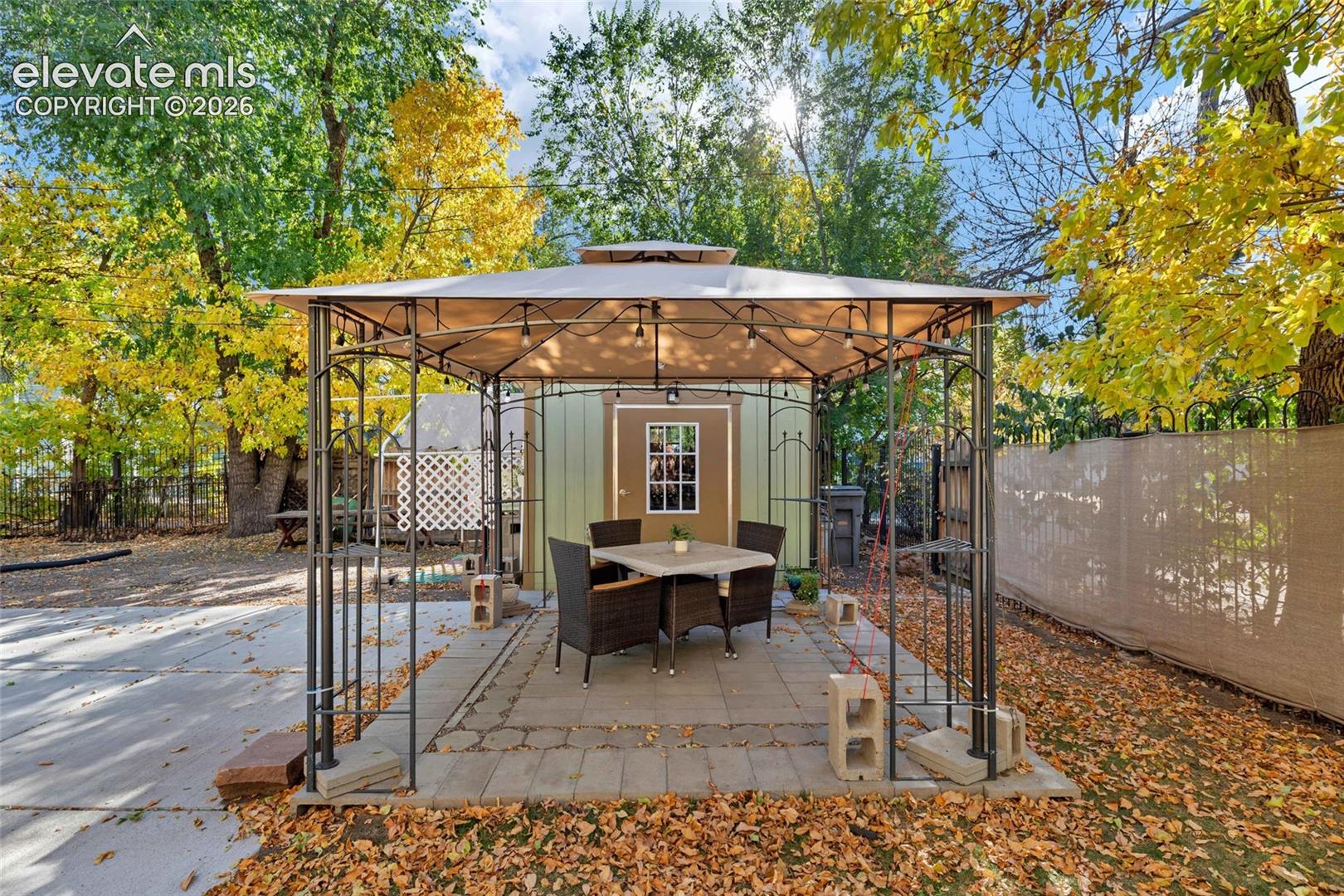 Backyard gazebo with a metal frame and overhead canopy situated on a paved patio surface