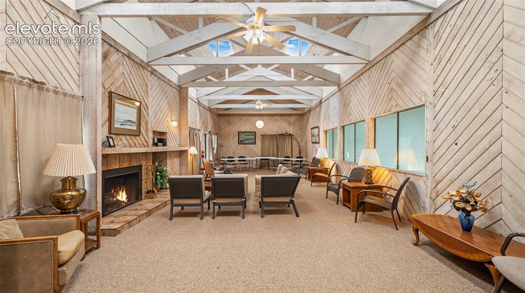 Spacious gathering area featuring vaulted ceilings with exposed beams, skylights, and multiple ceiling fans