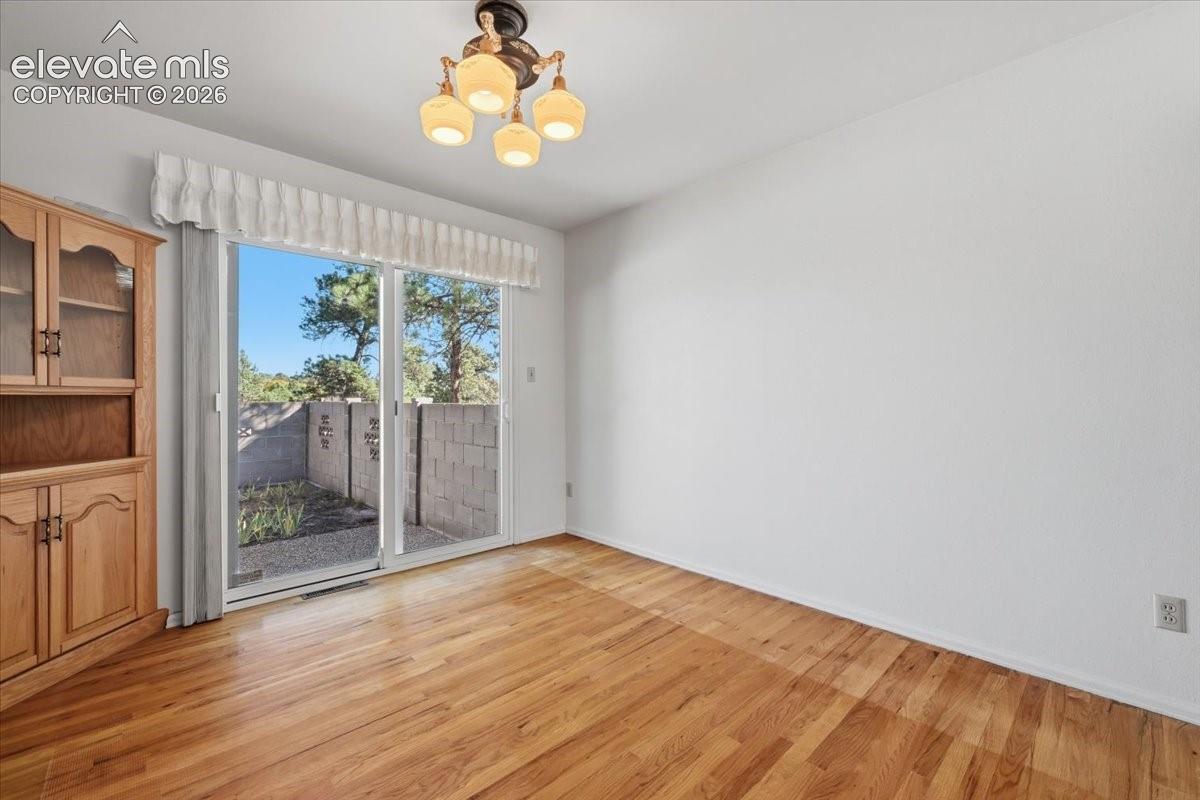 Wood-finish flooring, built-in wooden cabinetry, sliding glass door, and multi-light ceiling fixture