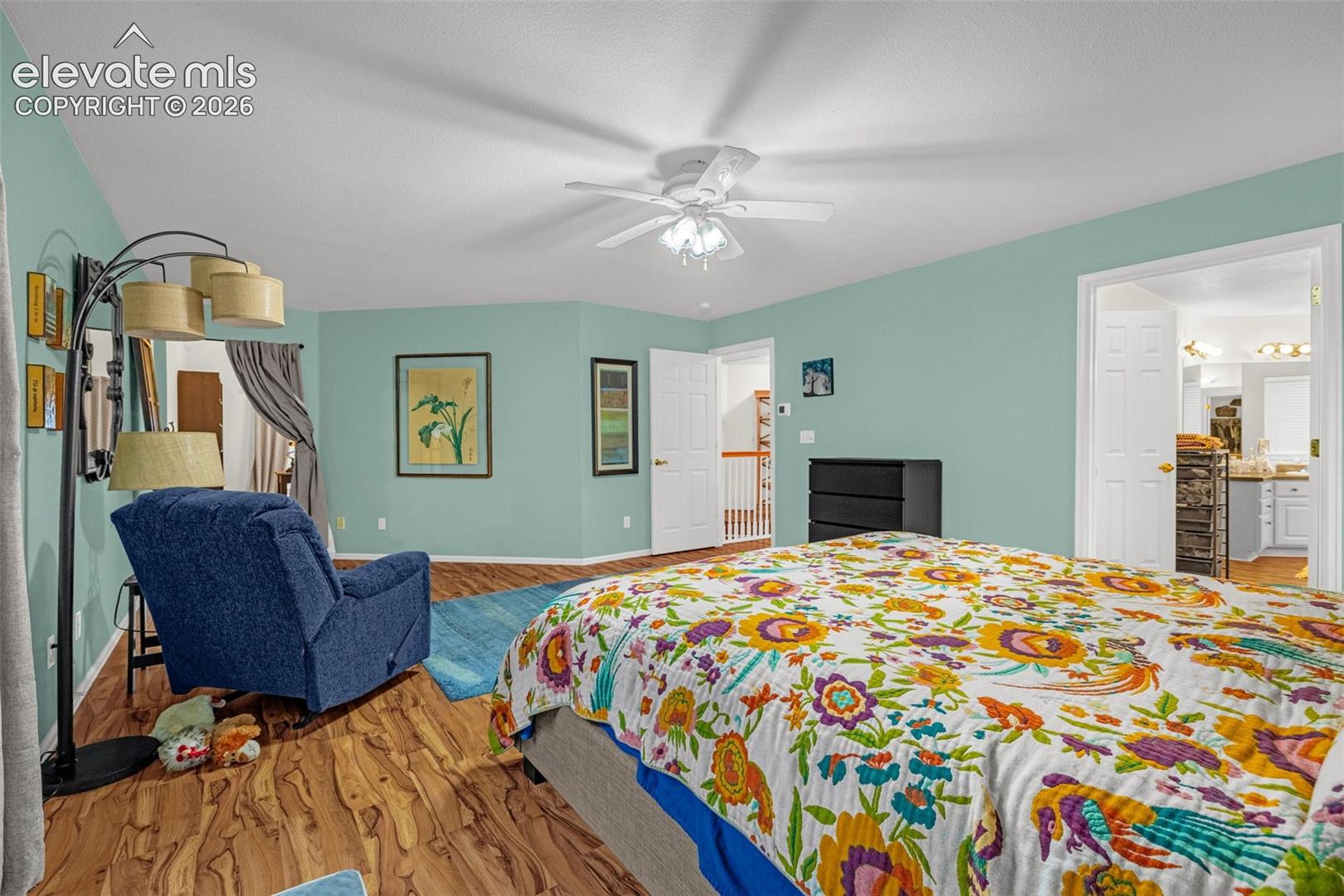 Wood-finish flooring throughout, ceiling fan with integrated lighting, and multiple entryways with paneled doors