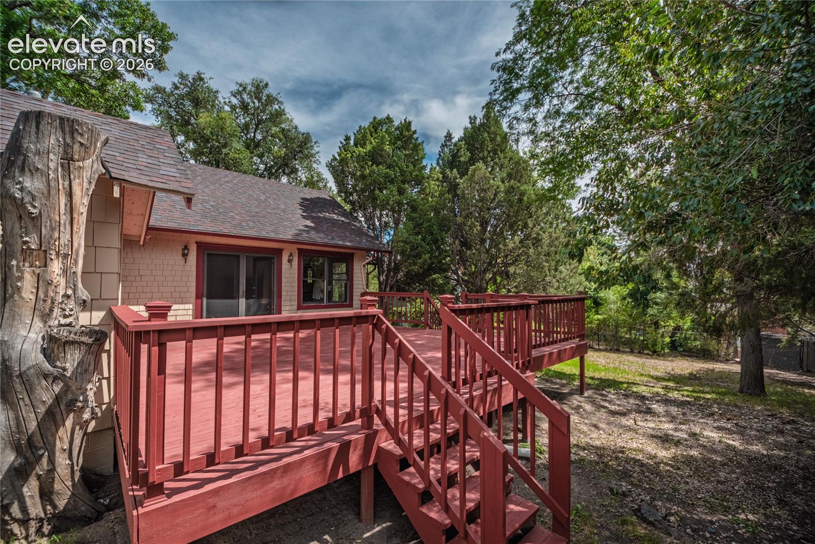 Expansive outdoor deck with red-painted railings and steps, featuring multiple glass-paned sliding doors