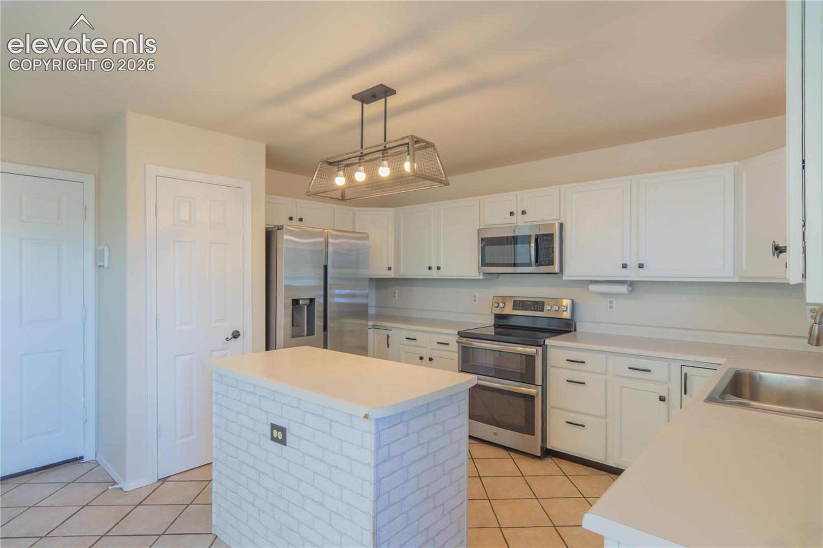 White cabinetry, stainless steel appliances, and a center island offer style and functionality.
