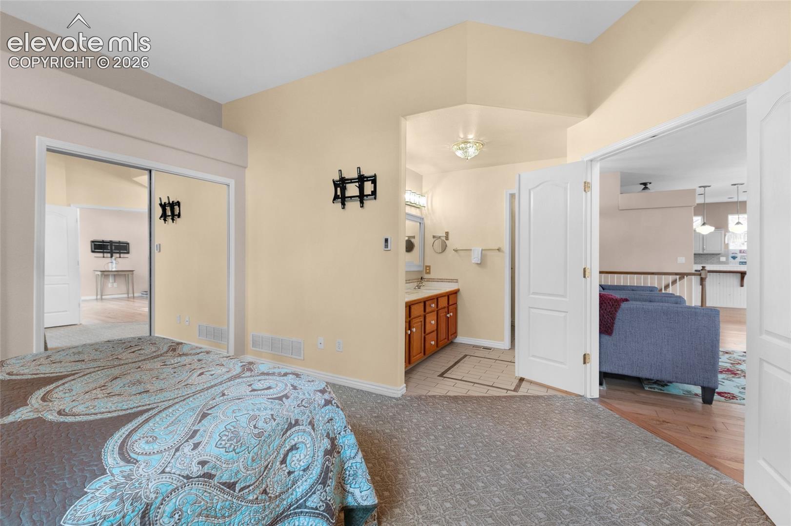 Vaulted ceiling, mirrored sliding closet doors, bathroom vanity with integrated countertop, and interior paneled doors