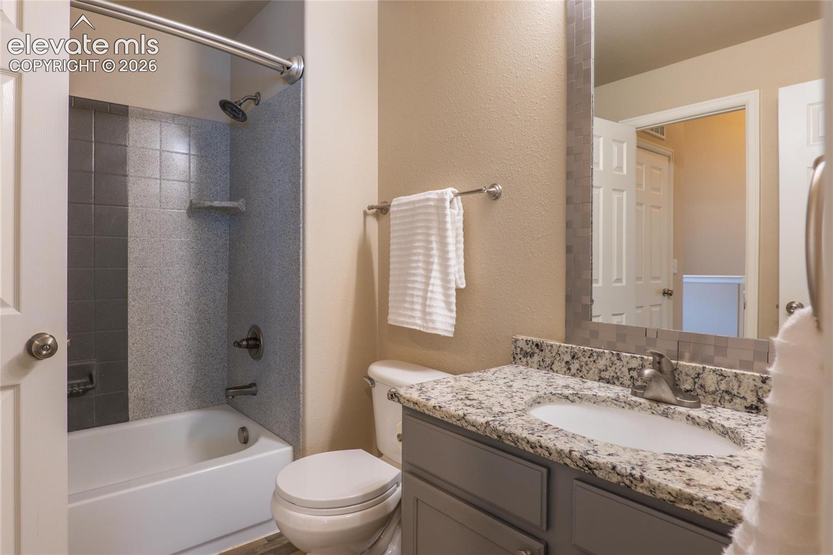 Upper full bath with granite counter and LVP flooring.