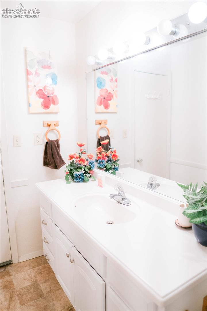 White vanity with integrated sink, chrome faucet, and expansive wall mirror