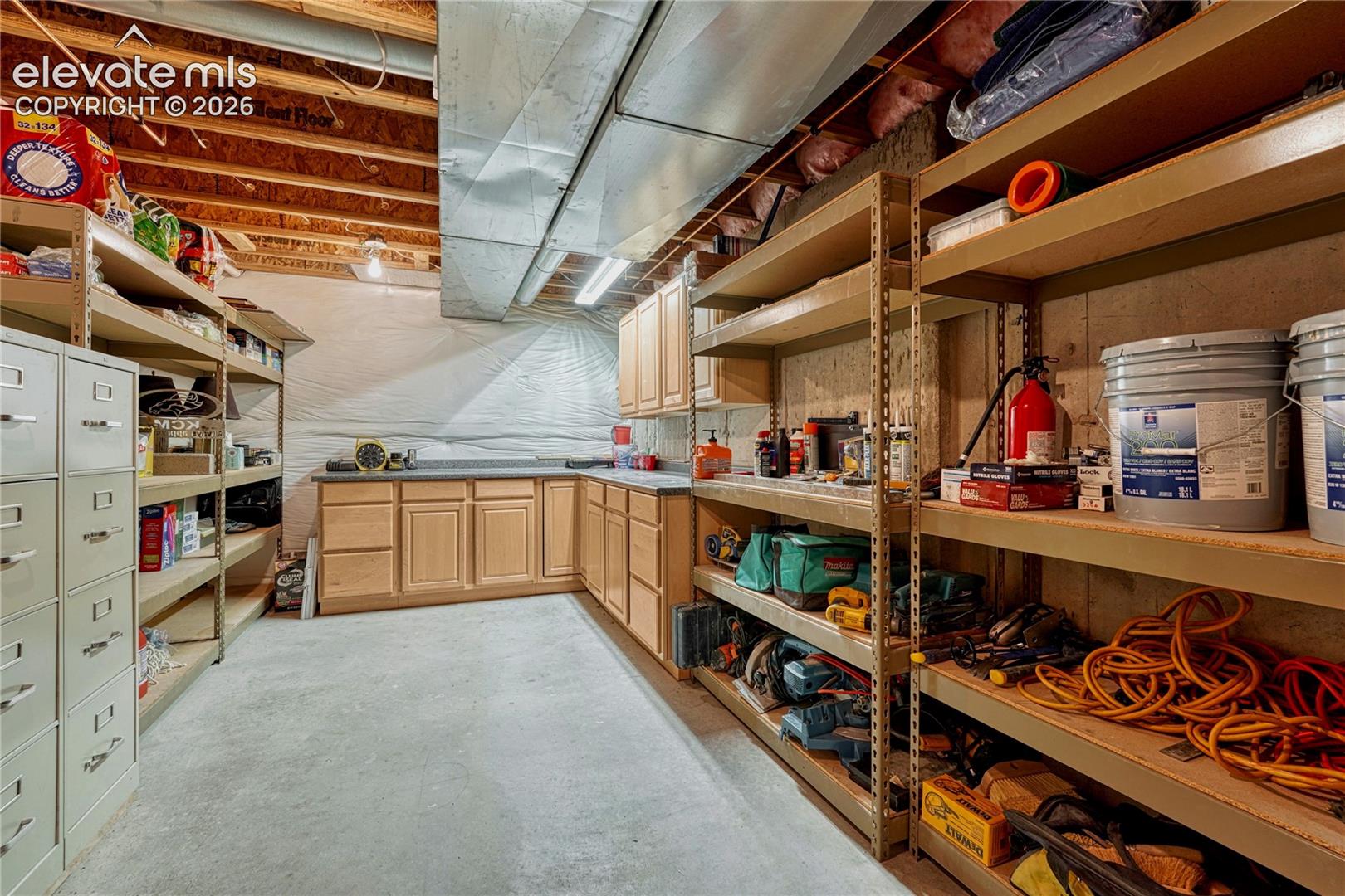 Fantastic unfinished workshop and utility area featuring extensive built-in oak cabinets and sturdy metal storage shelves stay with the house
