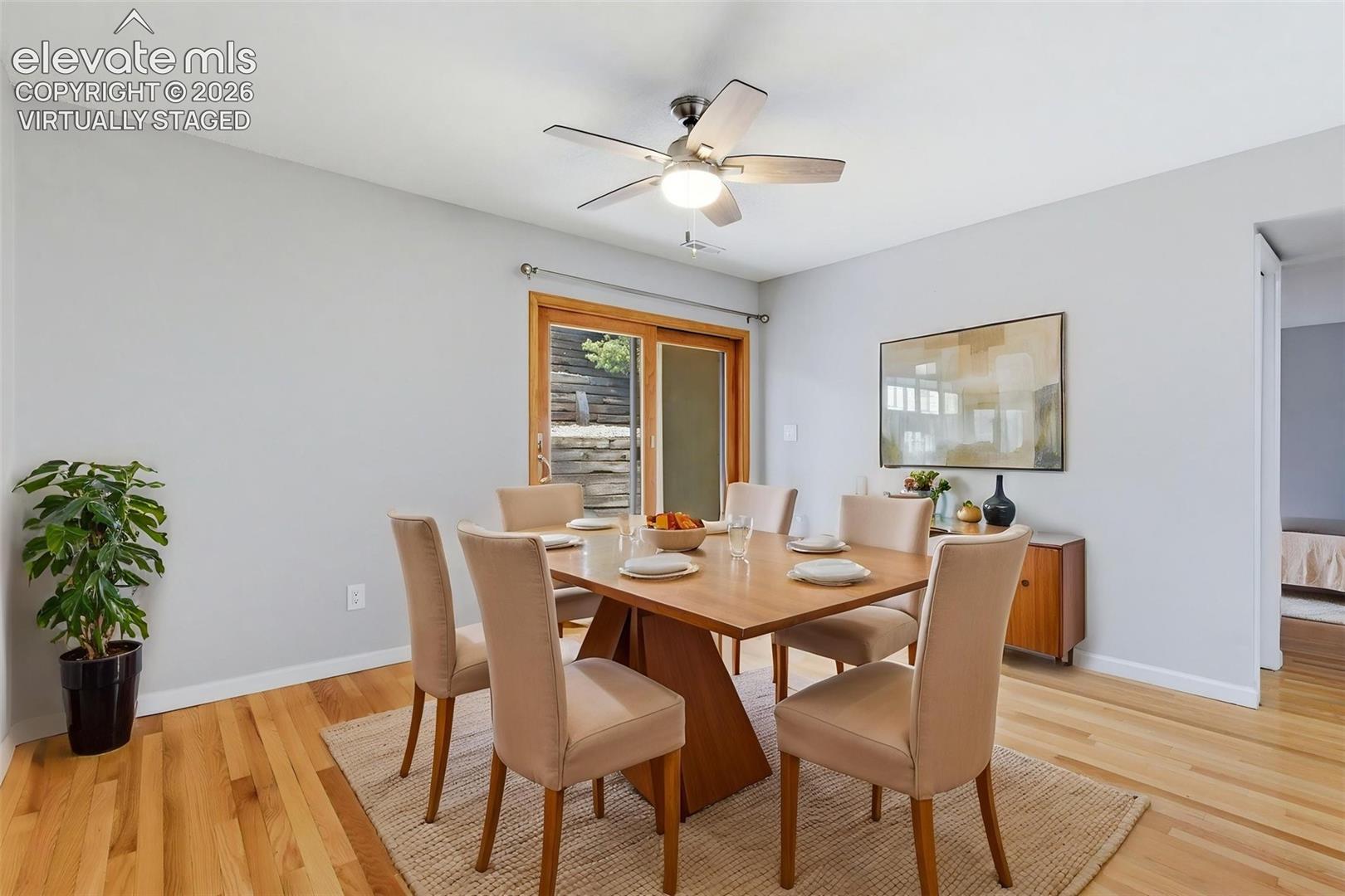 Virtually staged Dining area featuring hardwood flooring, a ceiling fan with integrated lighting, and a sliding glass door with wood trim