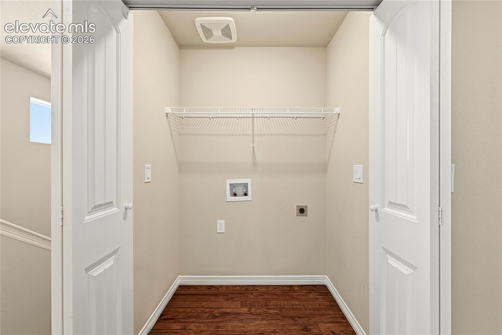 Dedicated laundry alcove featuring wood-finish flooring, a white wire shelf, and appliance hookups