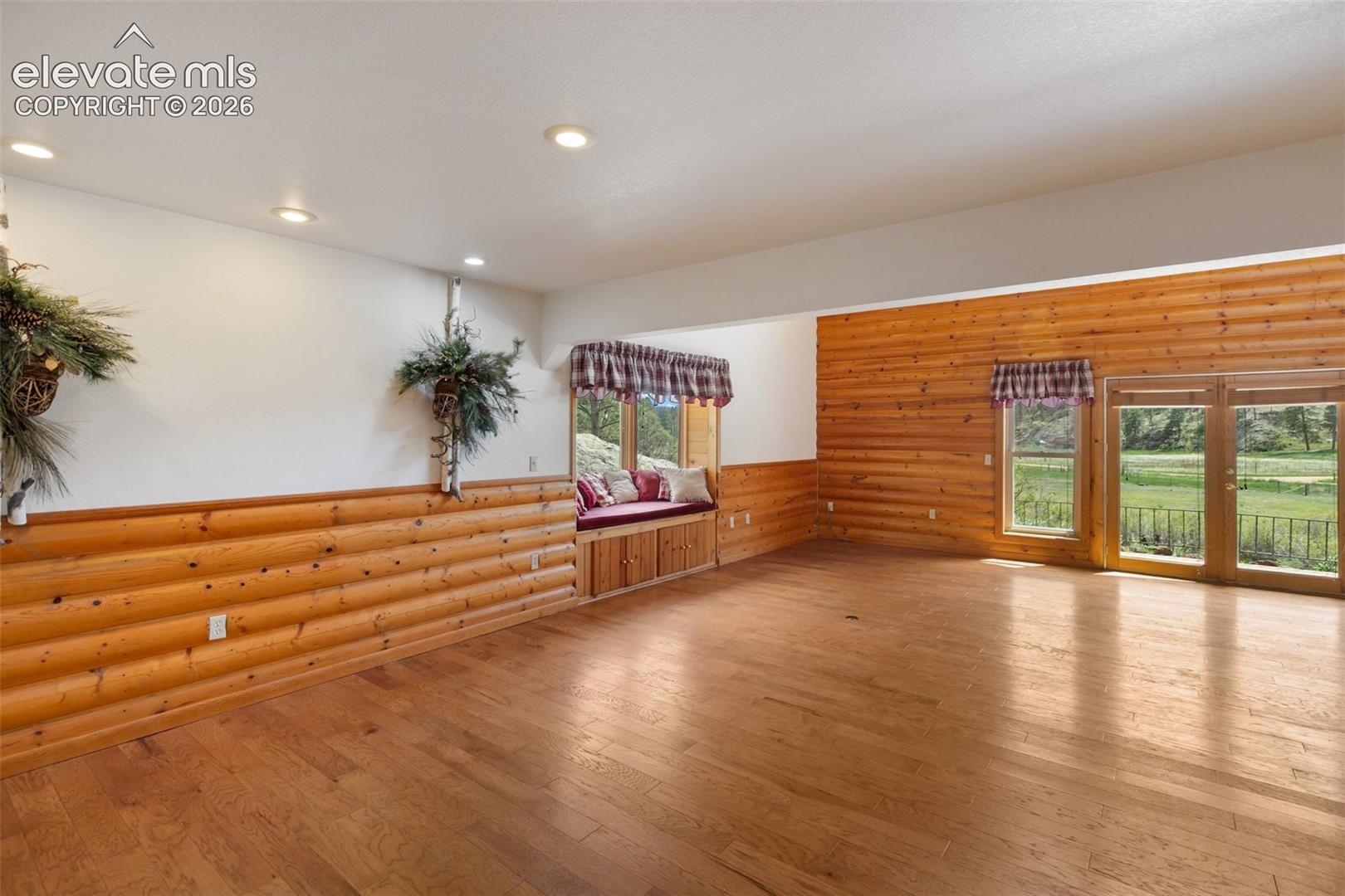 Dining and familya room featuring a rustic log cabin accent wall, a charming bay window, and a walk-out family room for easy outdoor access.