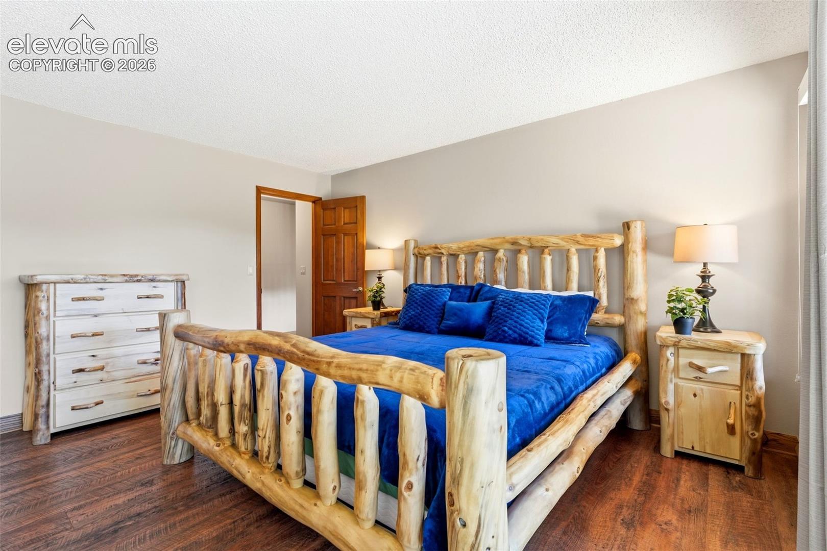 Wood-finish flooring, light neutral wall color, and a solid wood interior door