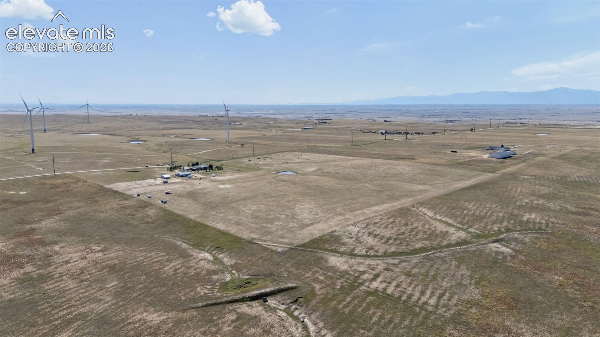 Aerial perspective of expansive open acreage featuring mountain horizon silhouettes and level terrain