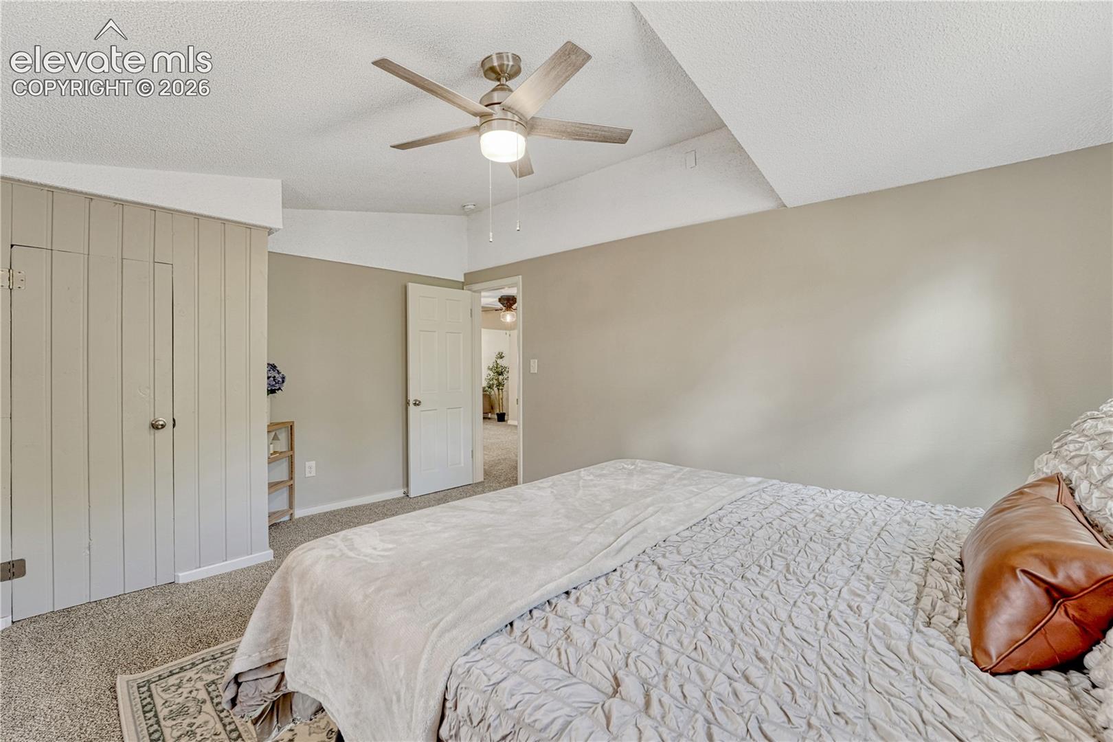 Textured carpeting throughout, featuring a ceiling fan with integrated lighting, and a neutral wall color
