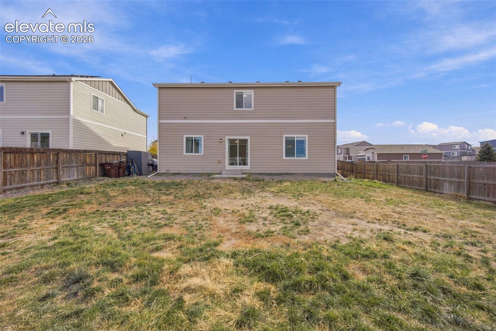 Rear exterior featuring horizontal lap siding, sliding glass doors, and a wood-slat privacy fence enclosing the yard