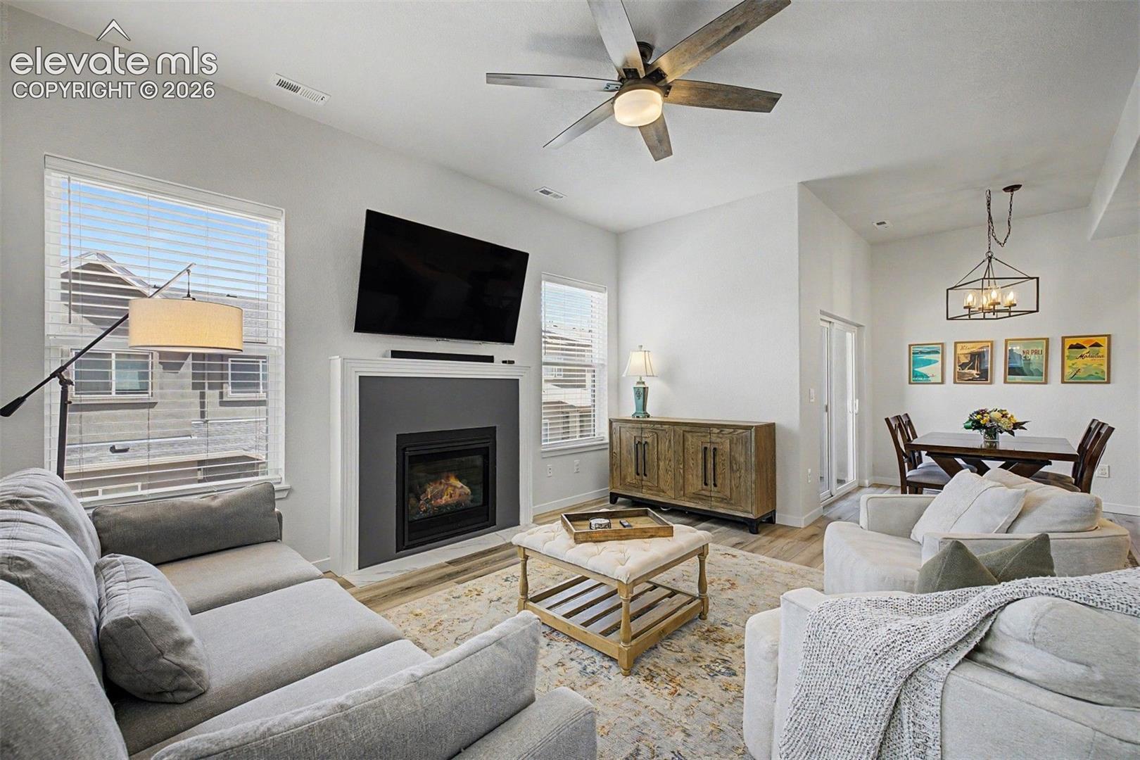 The gas fireplace is a showpiece on its own — framed in a crisp white mantel with a charcoal surround, flames dancing behind glass while soft furnishings pull the seating into a cozy, conversation-ready circle.