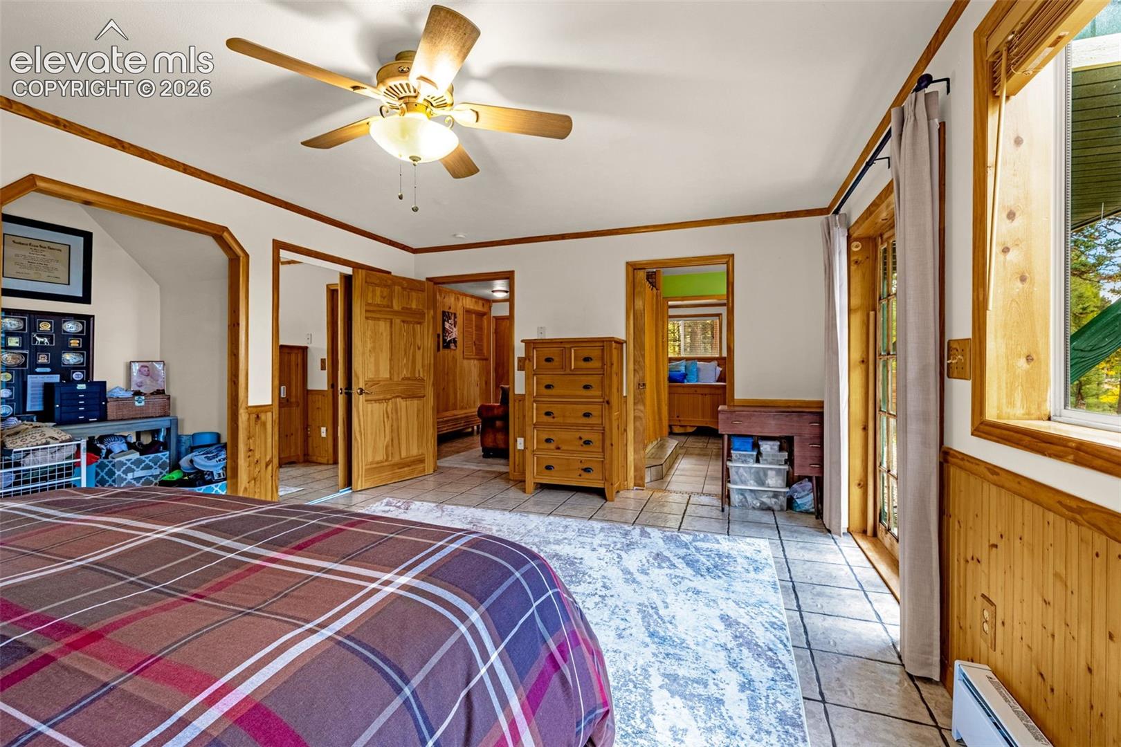 Interior featuring tile flooring, wood-paneled walls, multiple wood-finished interior doors, and a ceiling fan with integrated lighting