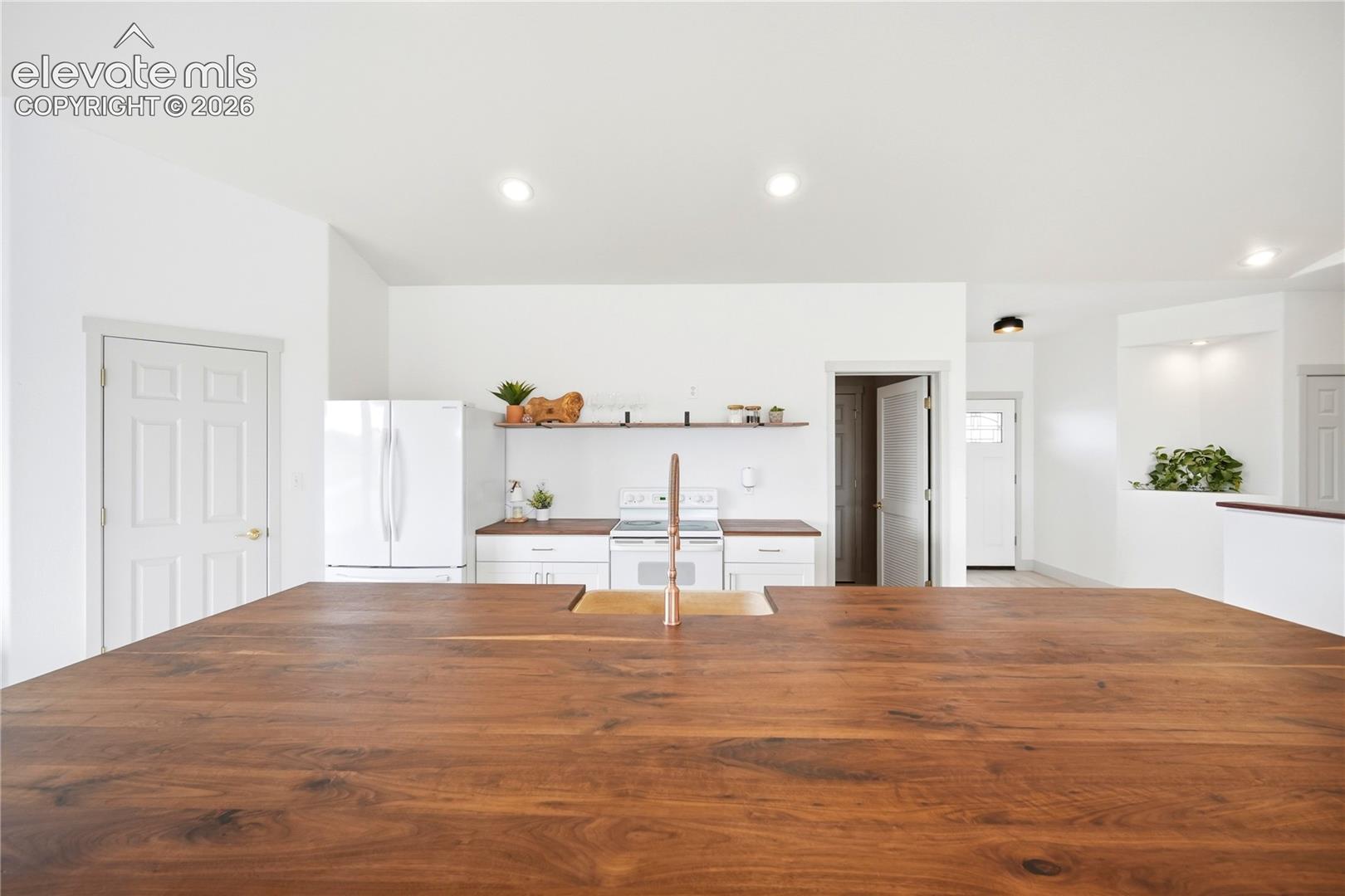 Kitchen featuring a large wood-finish island countertop, white cabinetry, dark wood-finish perimeter countertops, floating shelving, and recessed lighting