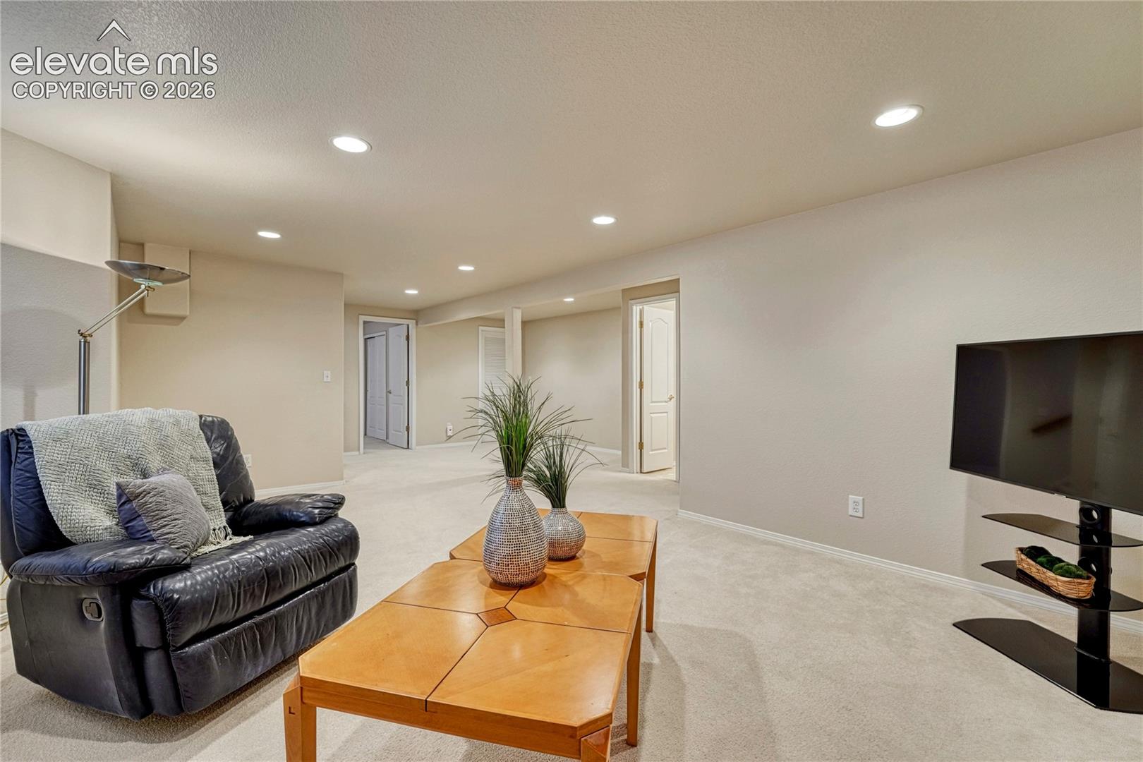 Wide perspective of the lower-level living area showing quick access to the basement bedrooms, full bath, and workshop
