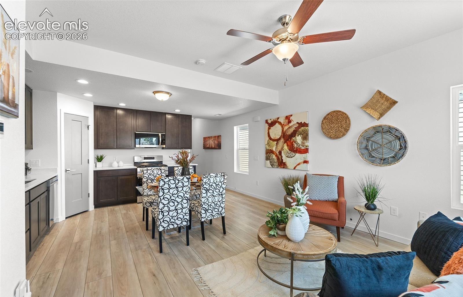 Open-concept area featuring wood-finish flooring, dark-toned cabinetry, recessed lighting, and a ceiling fan