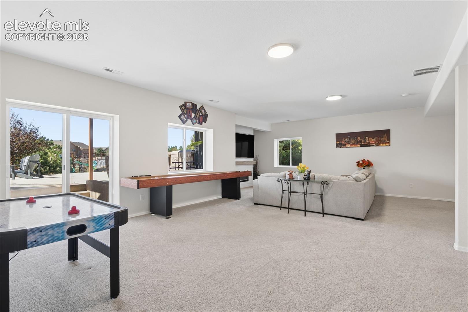 Expansive room with neutral carpet flooring, and large sliding glass doors leading to an outdoor patio