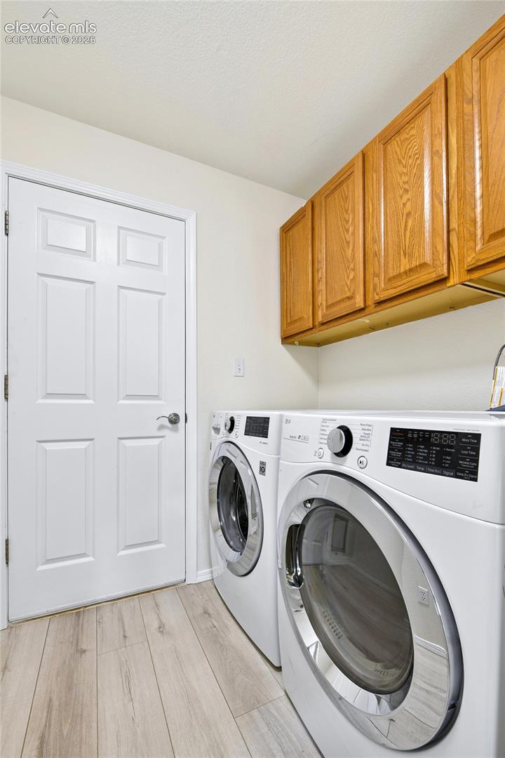Light wood-finish flooring, white paneled door, and natural wood cabinetry Off of the garage 