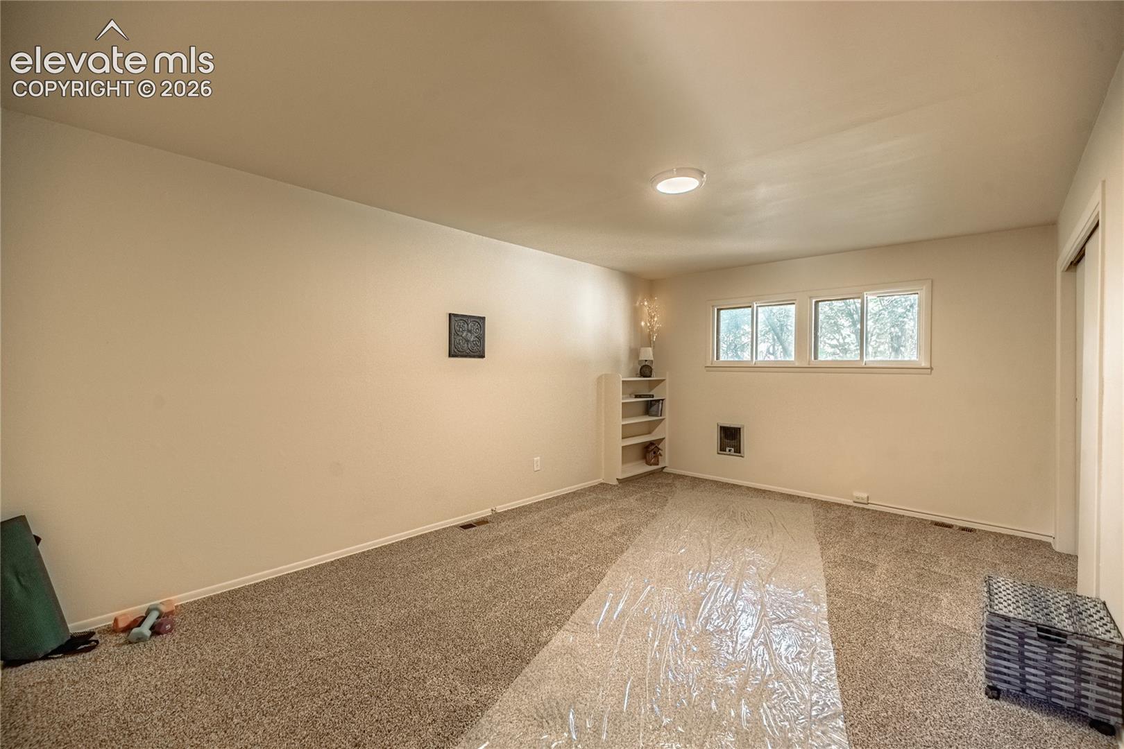 Neutral wall paint, built-in shelving, and three windows with natural light