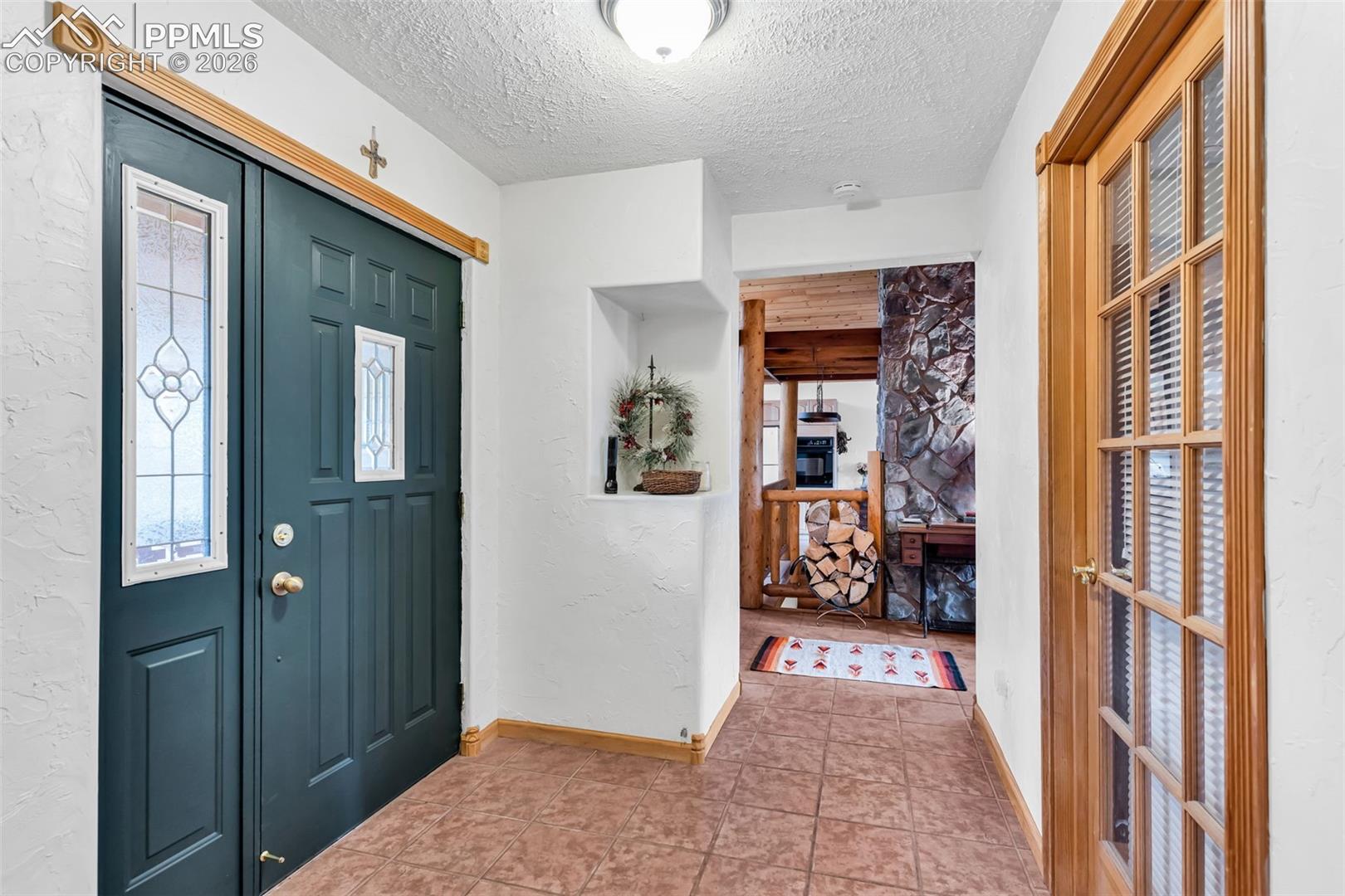 Tile floors and coat closet upon entry, with glass door to the office/living room