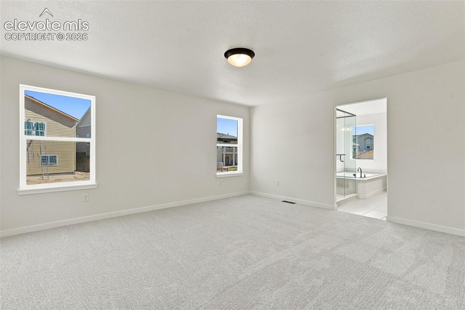 Spacious Primary Bedroom room with soft white walls, light-light gray carpeting, and a flush-mount ceiling light.