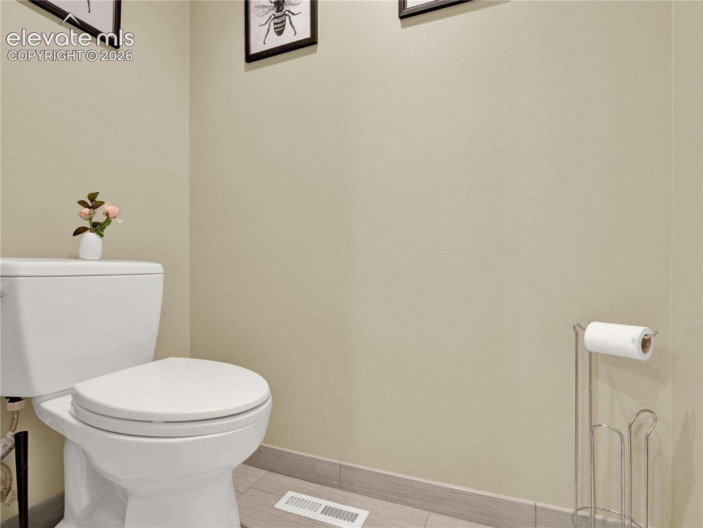 White elongated porcelain toilet with a matching tank and neutral-toned wall finish