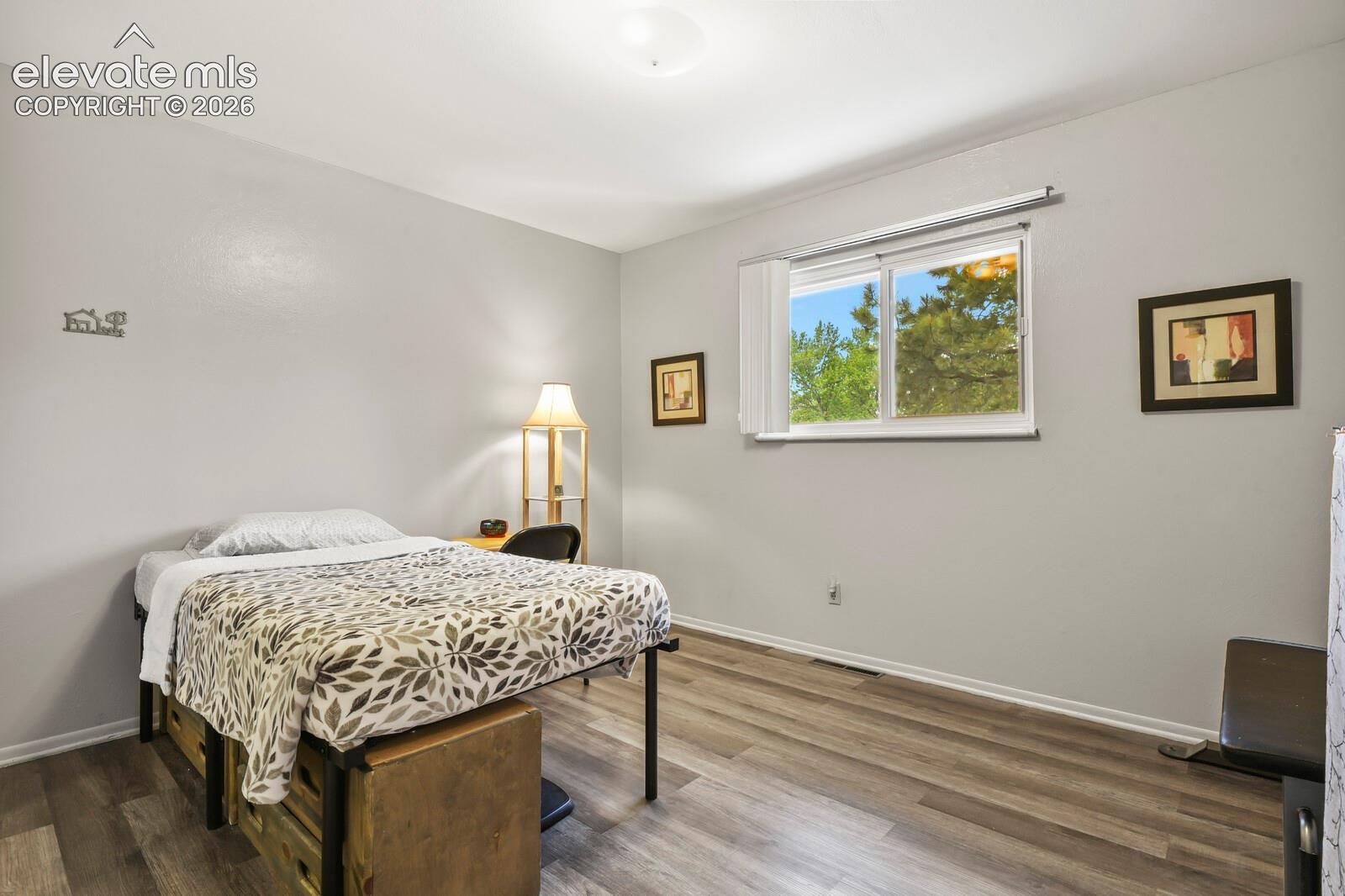 Room featuring wood-finish flooring, light grey painted walls, and white trim