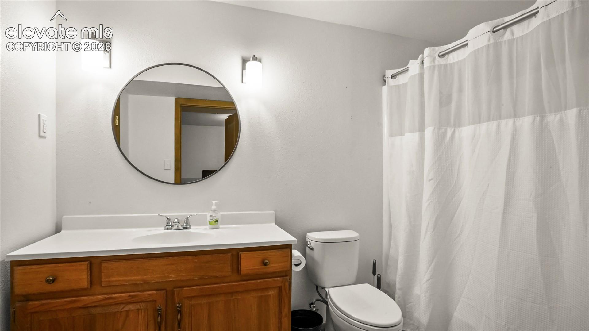 Adjoining bathroom in the basement, with vanity with wood-finish cabinetry, white countertop, and integrated sink, LVP flooring