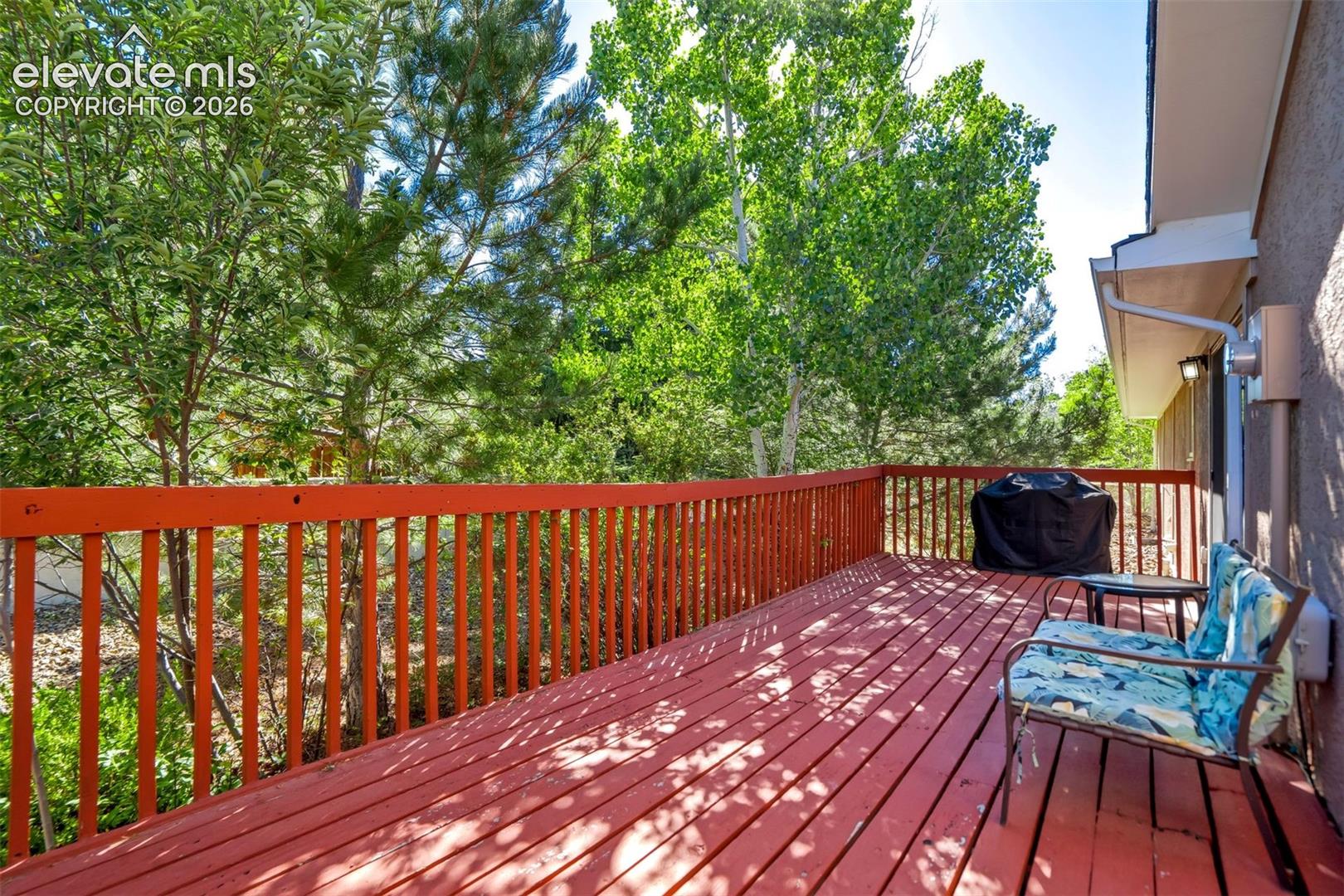 Spacious wood deck with a red finish, offering an outdoor living area
