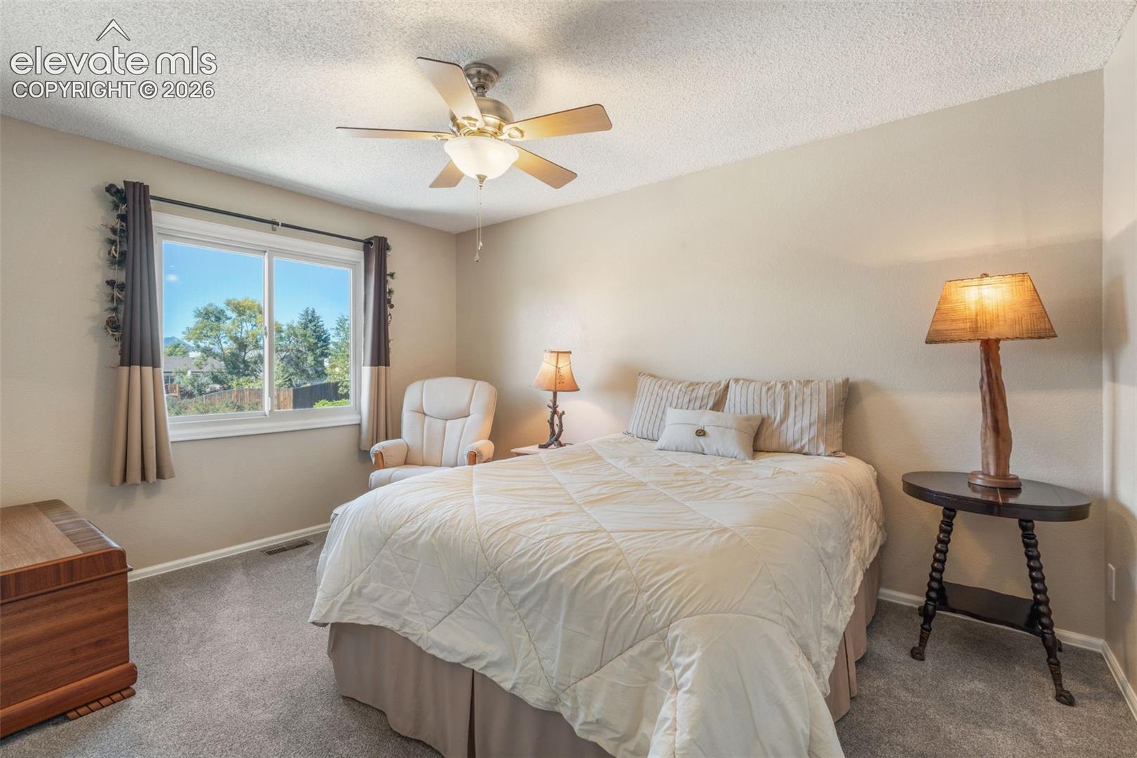 Bedroom featuring neutral-toned walls, wall-to-wall carpeting, a multi-blade ceiling fan with an integrated light fixture, and a dual-pane window