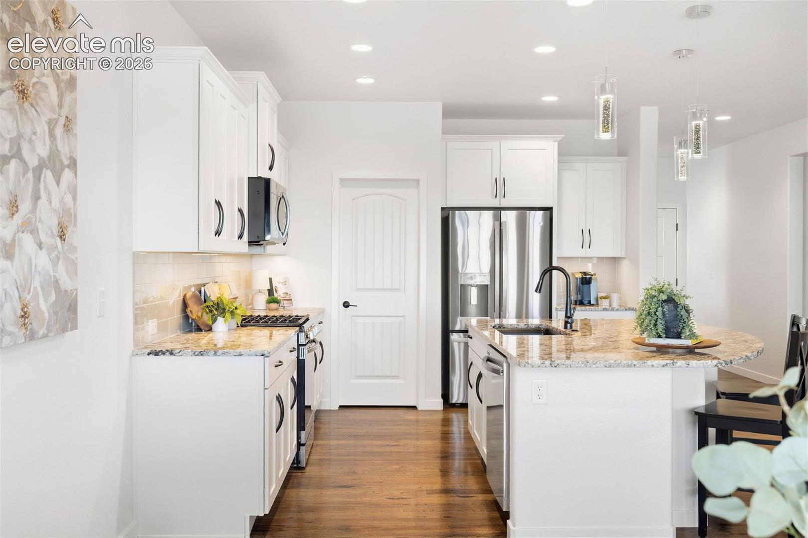 View of the kitchen from the dining area. Real hardwood floors continue through the kitchen. 