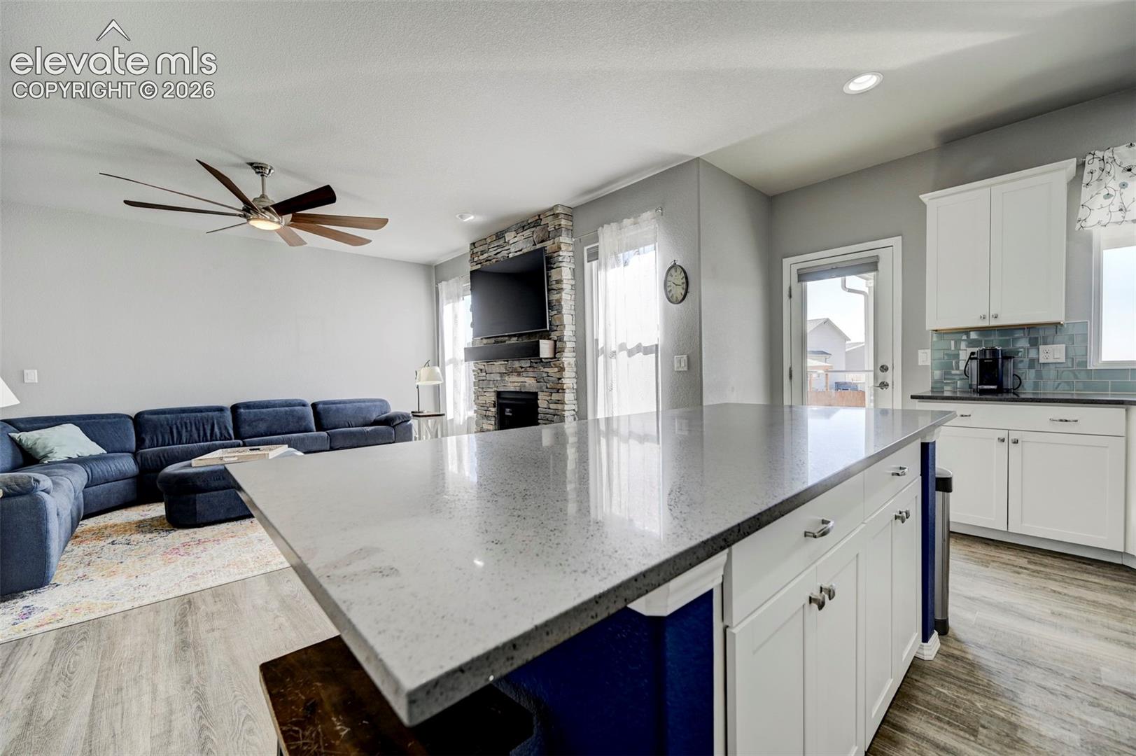 Kitchen island featuring a speckled countertop and white shaker-style cabinetry with chrome hardware