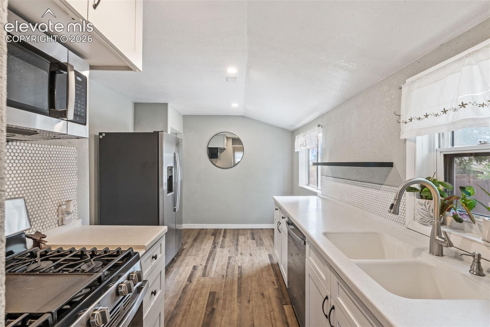 Kitchen featuring white cabinetry, light countertops, and wood-finish flooring