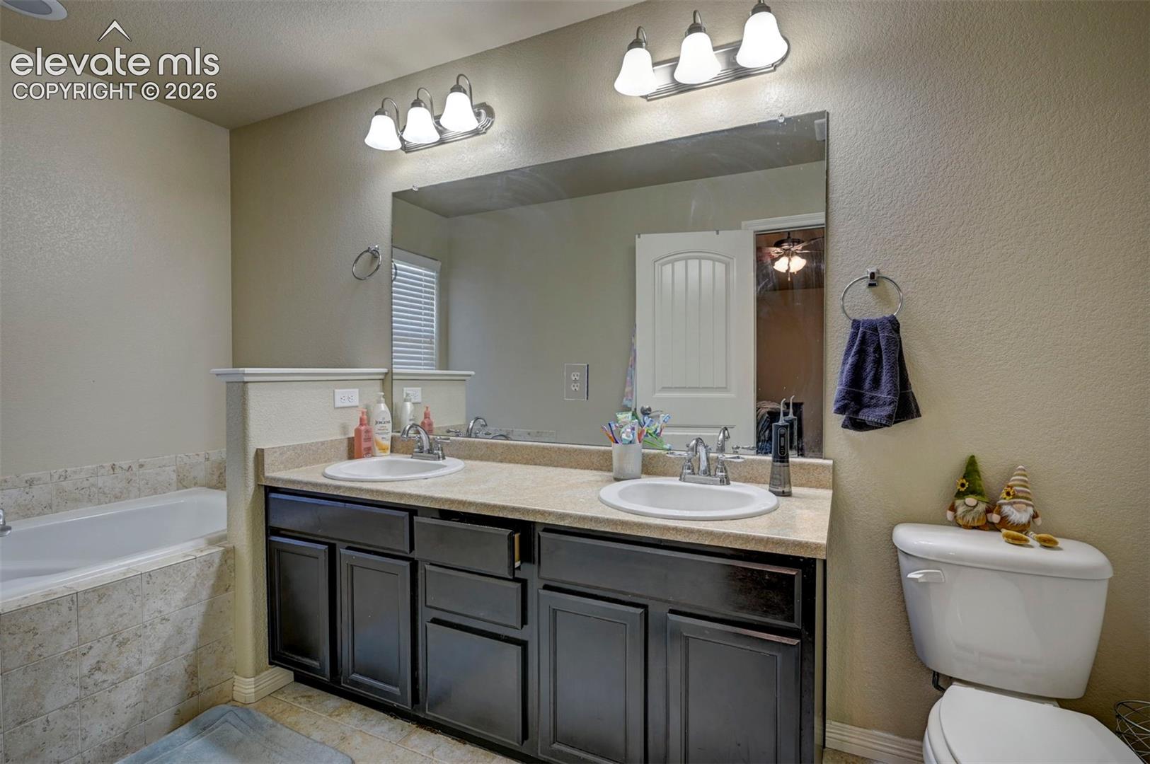 Dual vanity with integrated sinks, a large wall-mounted mirror, and overhead lighting