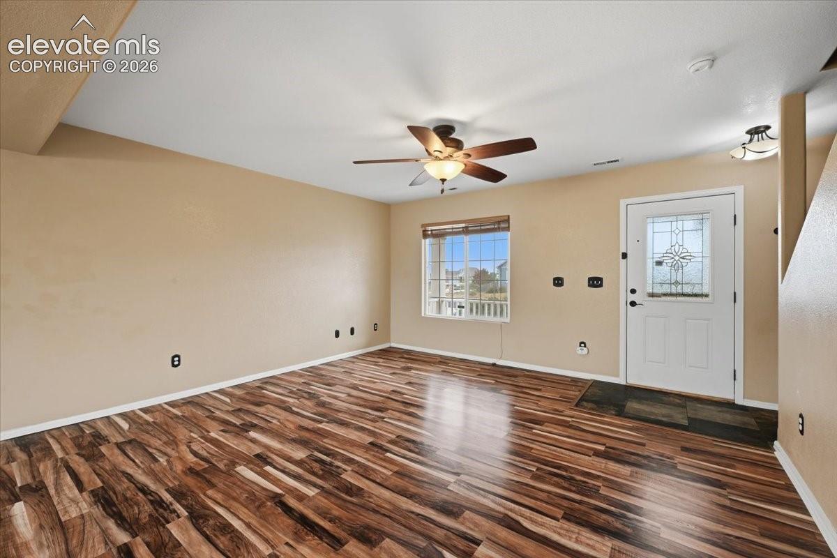 Wood-finish flooring, decorative glass entry door, ceiling fan with integrated lighting, recessed window, and neutral wall tones
