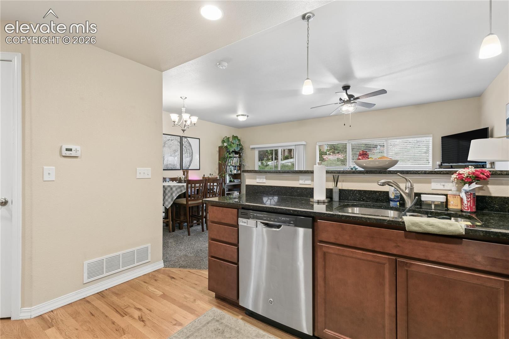 Kitchen featuring wood-finish flooring, dark wood cabinetry, and a dark stone countertop with an undermount sink