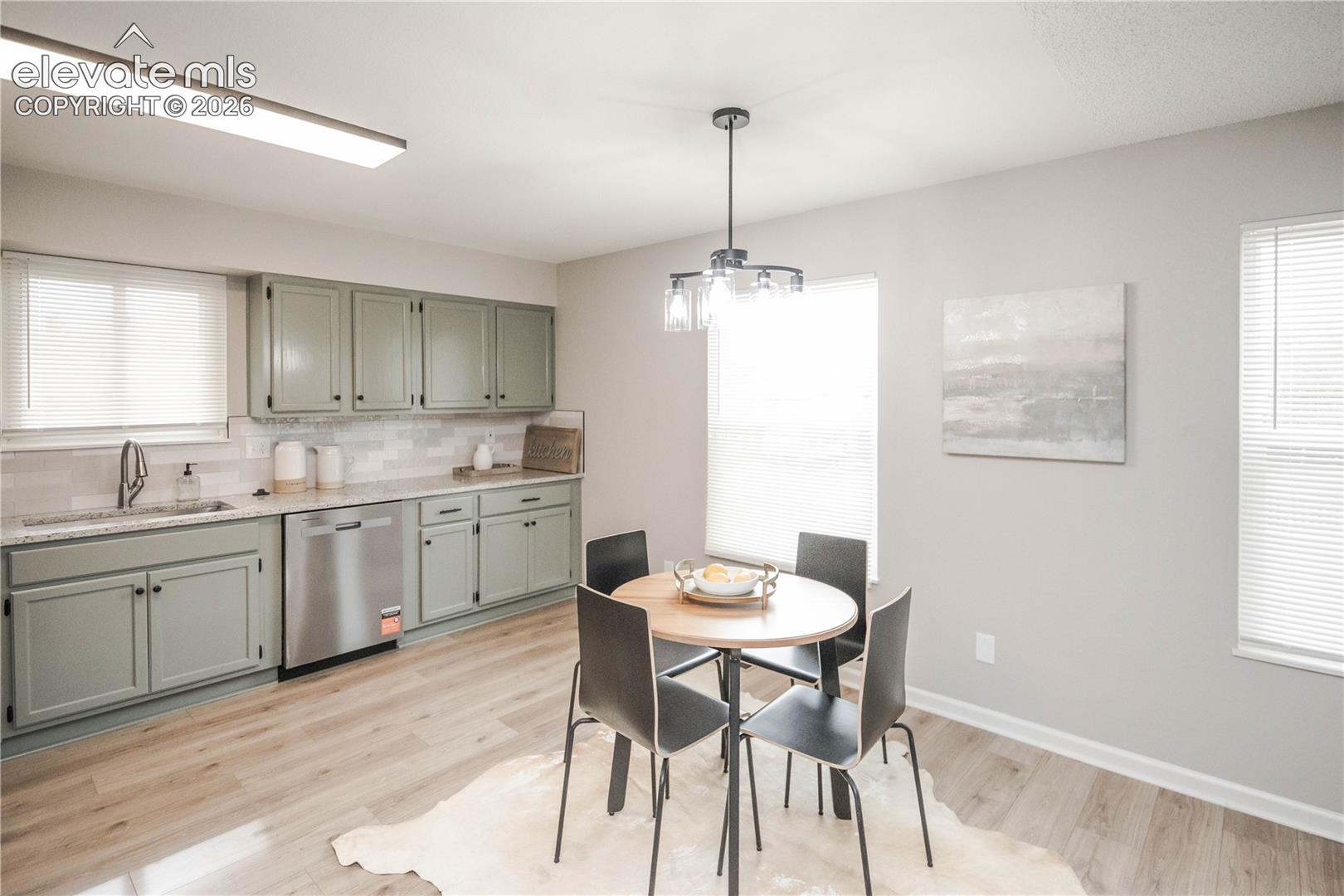 Kitchen featuring soft-green cabinetry, stone-finish countertops, stainless steel dishwasher, linear overhead lighting, and wood-finish flooring