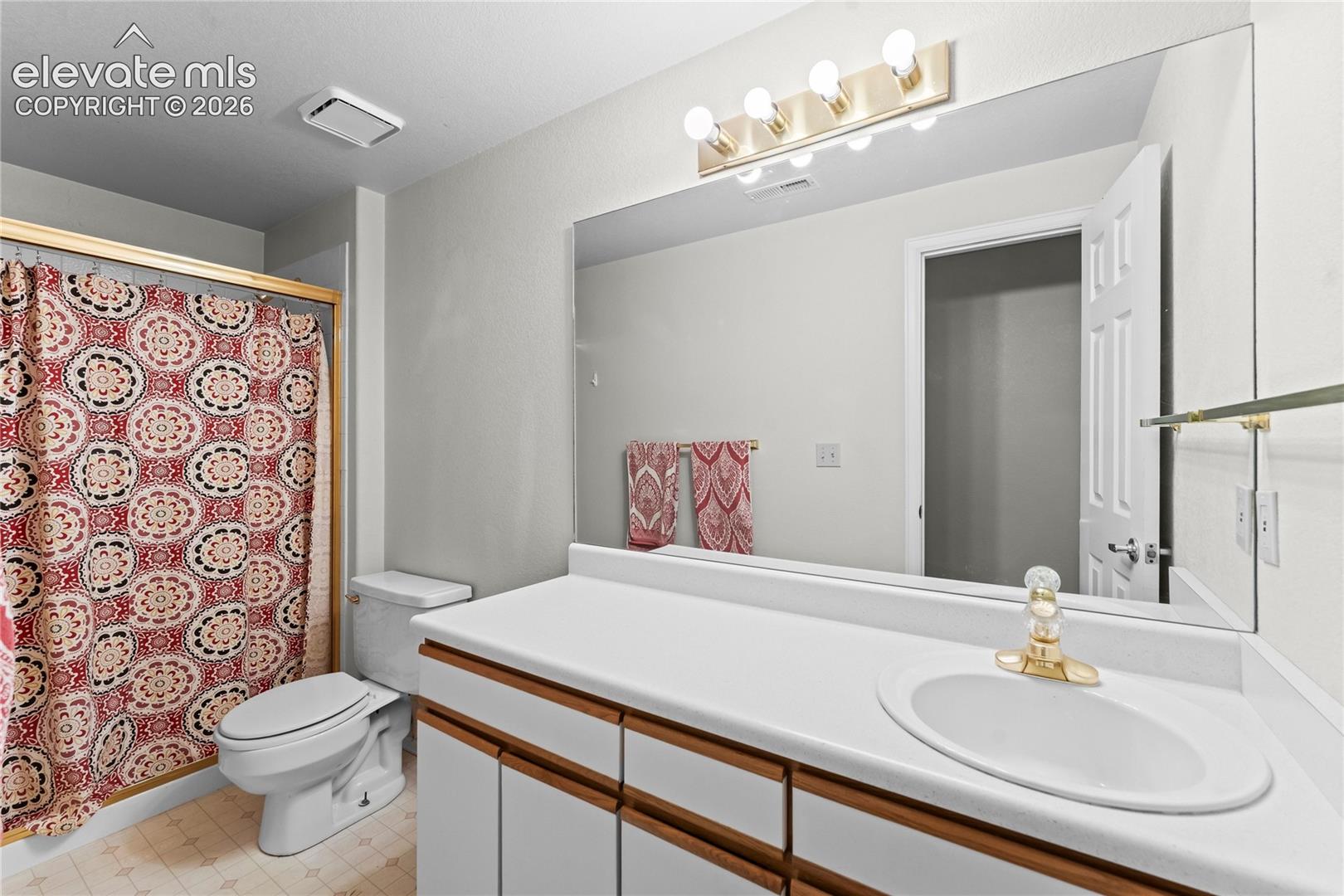 Corner vanity with integrated sink, gold-tone faucet, and expansive wall-mounted mirror