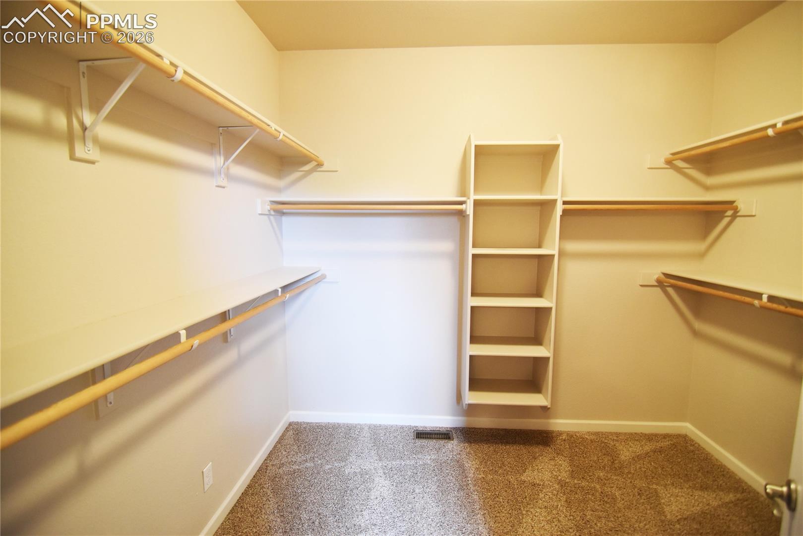 Spacious walkin closet with lots of rods and built-in shelves.