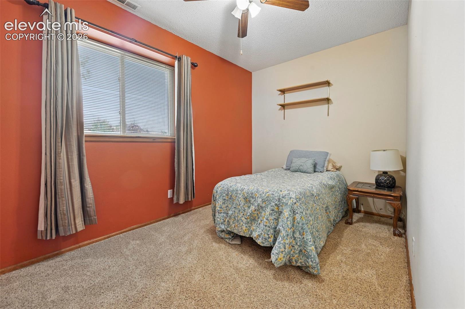 Basement bedroom with plush carpeting and a ceiling fan with light fixture