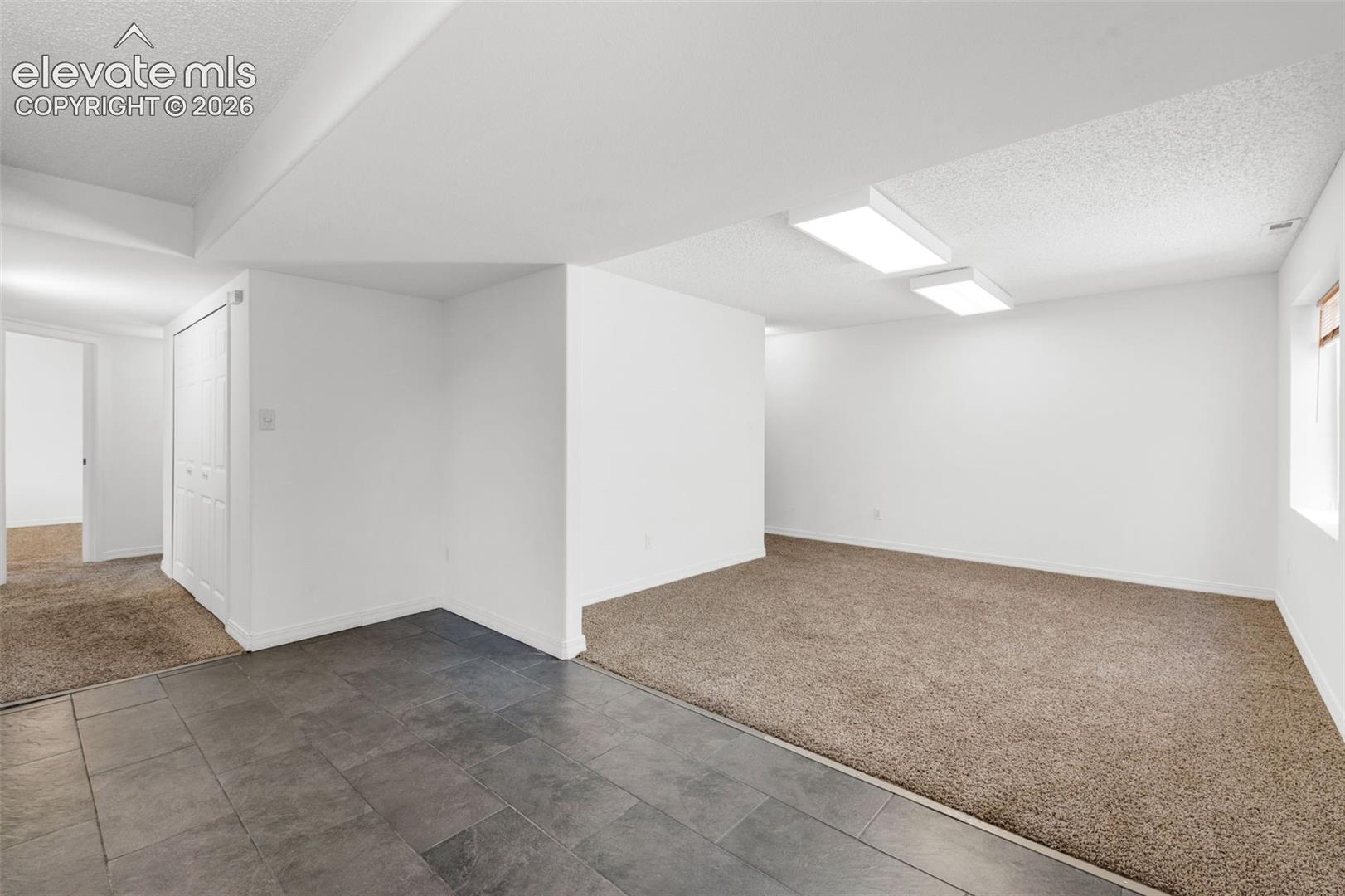 Spacious room featuring broadloom carpeting, recessed lighting, and a window for natural light