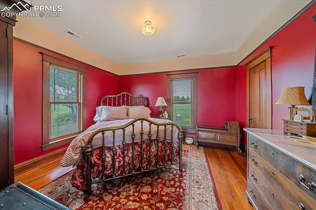 Bedroom featuring wood finished floors and multiple windows